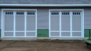 Two light grey garage doors with white trim installed on a new construction home by Superior Overhead Door, LLC in Granger, IN