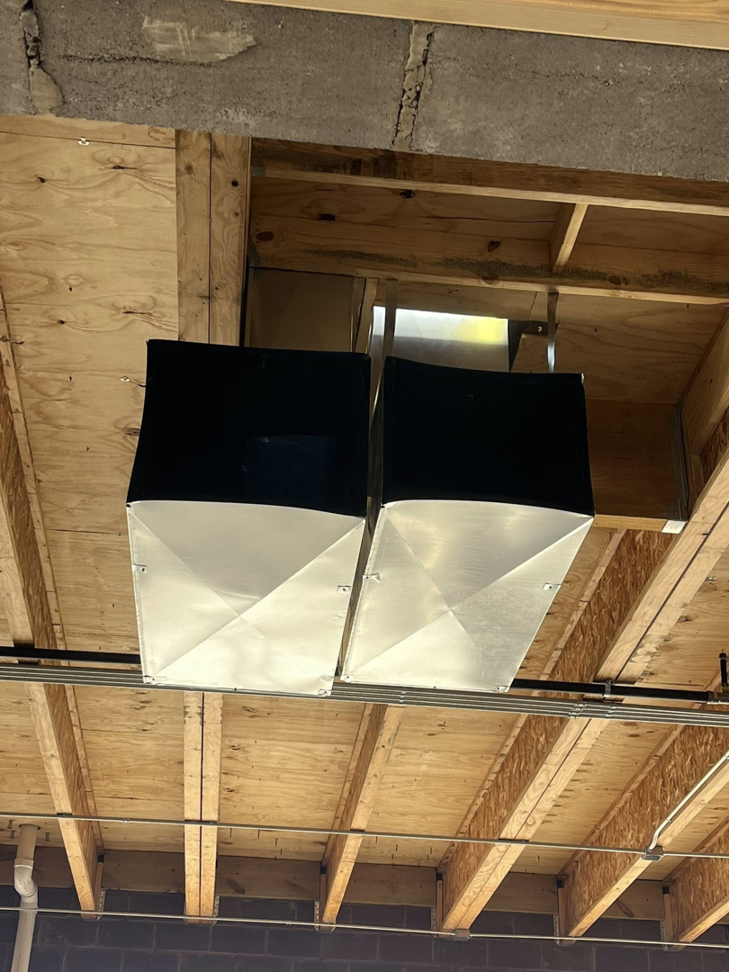 Two sections of metal HVAC ductwork installed in a commercial ceiling by Airman Solutions Inc in Oklahoma City, OK