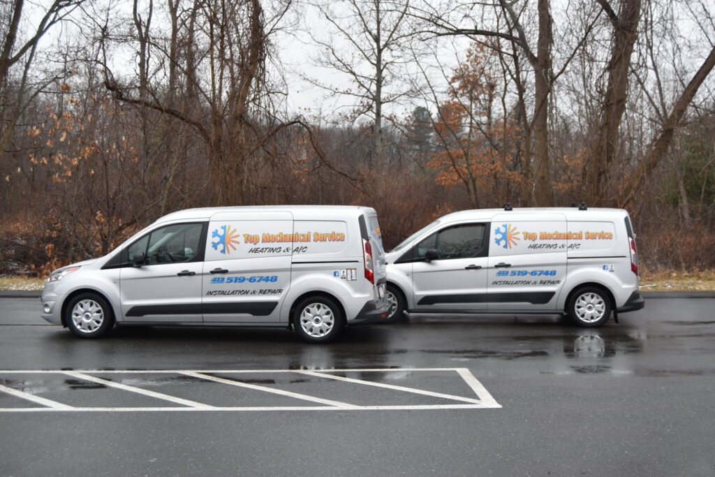 Two branded HVAC service vans parked side-by-side, ready for calls from Top Mechanical Service in East Longmeadow, MA.