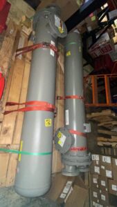 Two tall grey cylindrical HVAC system tanks strapped on pallets in a warehouse at Thermoflo Equipment in Pittsburgh, PA
