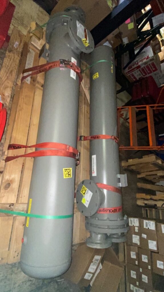 Two tall grey cylindrical HVAC system tanks strapped on pallets in a warehouse at Thermoflo Equipment in Pittsburgh, PA