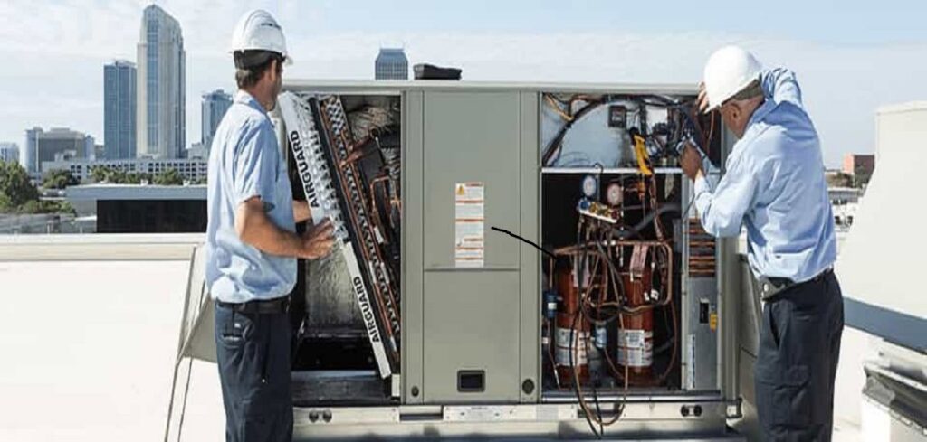 Two HVAC technicians performing maintenance on a large rooftop HVAC unit for Energy Logix in Austin, TX.