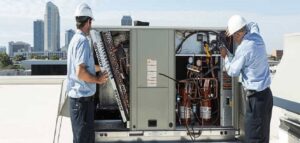 Two HVAC technicians performing maintenance on a large rooftop HVAC unit for Energy Logix in Austin, TX.