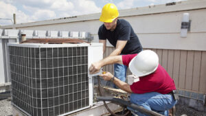 Two HVAC technicians servicing a rooftop air conditioning unit for Boykin Air Conditioning Services in Sumter, SC.