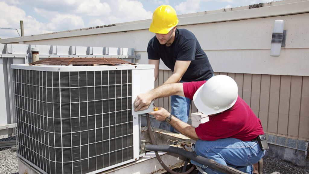 Two HVAC technicians servicing a commercial rooftop air conditioning unit for One Way Service Pros in Deadwood, SD.