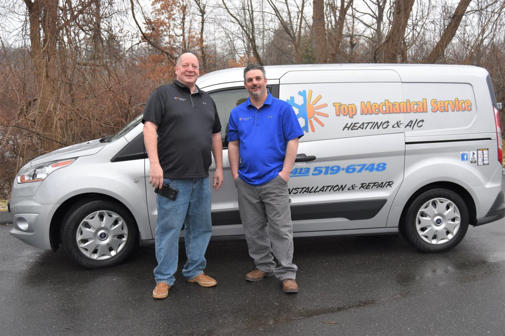 Two HVAC technicians standing proudly with their branded service van for Top Mechanical Service in East Longmeadow, MA.