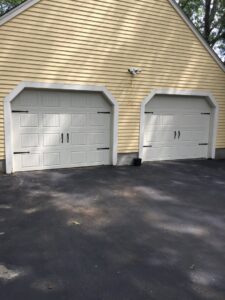 Two light beige garage doors with decorative hardware and top windows installed by Snowbird Garage Doors Company in Worcester, MA.