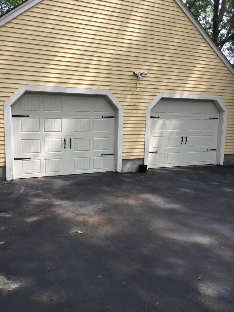 Two light beige garage doors with decorative hardware and top windows installed by Snowbird Garage Doors Company in Worcester, MA.