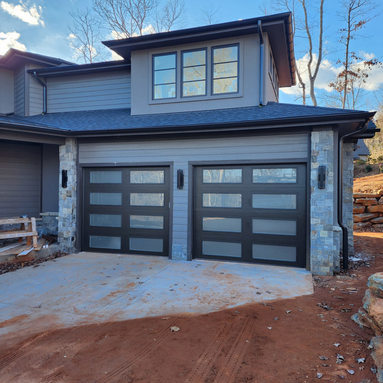 Two modern black garage doors with frosted glass panels installed by Getsinger's Overhead Doors in Spartanburg, SC.