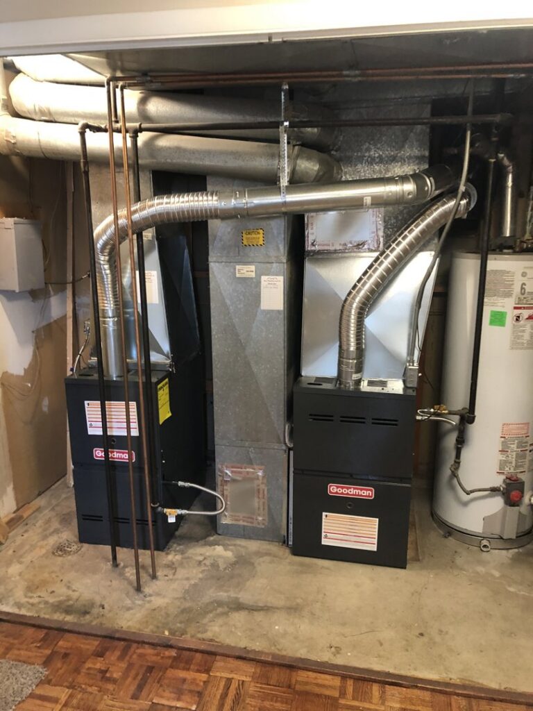Two new Goodman furnaces and a water heater with ductwork installed in a basement utility area by EPIC Heating and Air in Loveland, CO