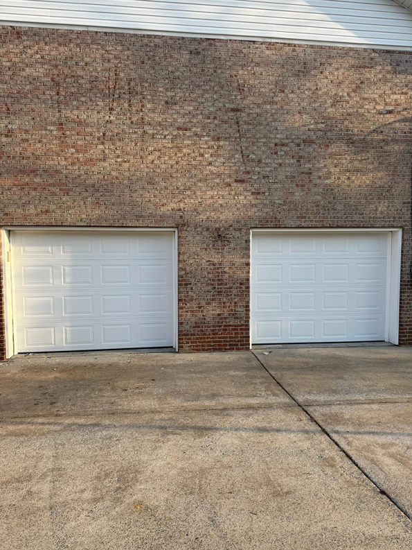 Two newly installed white panel garage doors on a brick building by J&S Garage Door Services in Franklin, TN.