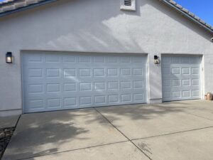 Two new white panel garage doors installed on a residential home by Tucson Garage Door Doc in Tucson, AZ.