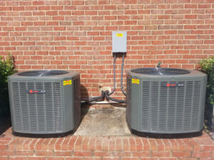 Two outdoor AC condenser units installed next to a brick building by C&K Air and Heating, Inc. in Olive Branch, MS.