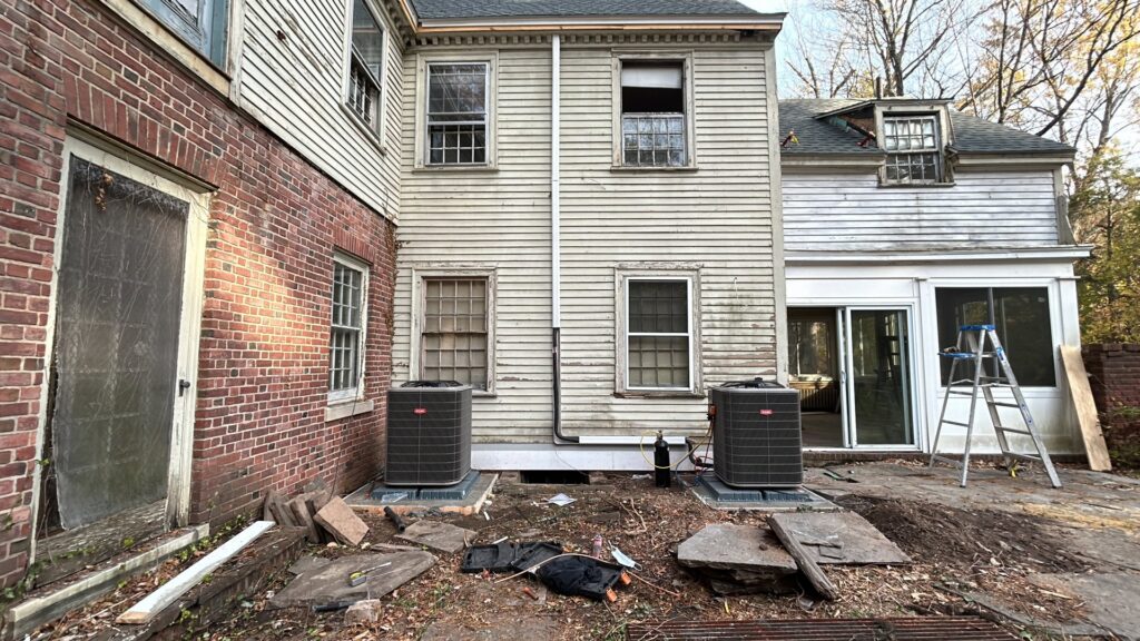 Two outdoor air conditioning condenser units installed next to an older residential building by Express Home Services LLC in Las Vegas, NV.