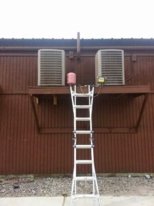 Two outdoor AC condenser units installed on a platform with a ladder for service by Calloway & Sons A/C And Heating in New Orleans, LA.