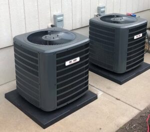 Two outdoor AC condenser units installed next to a residential building by One Hour Heating & Air Conditioning of West Valley in Phoenix, AZ