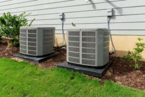 Two outdoor air conditioning condenser units installed next to a residential building by PNW Spokane Heating and Air in Spokane, WA.