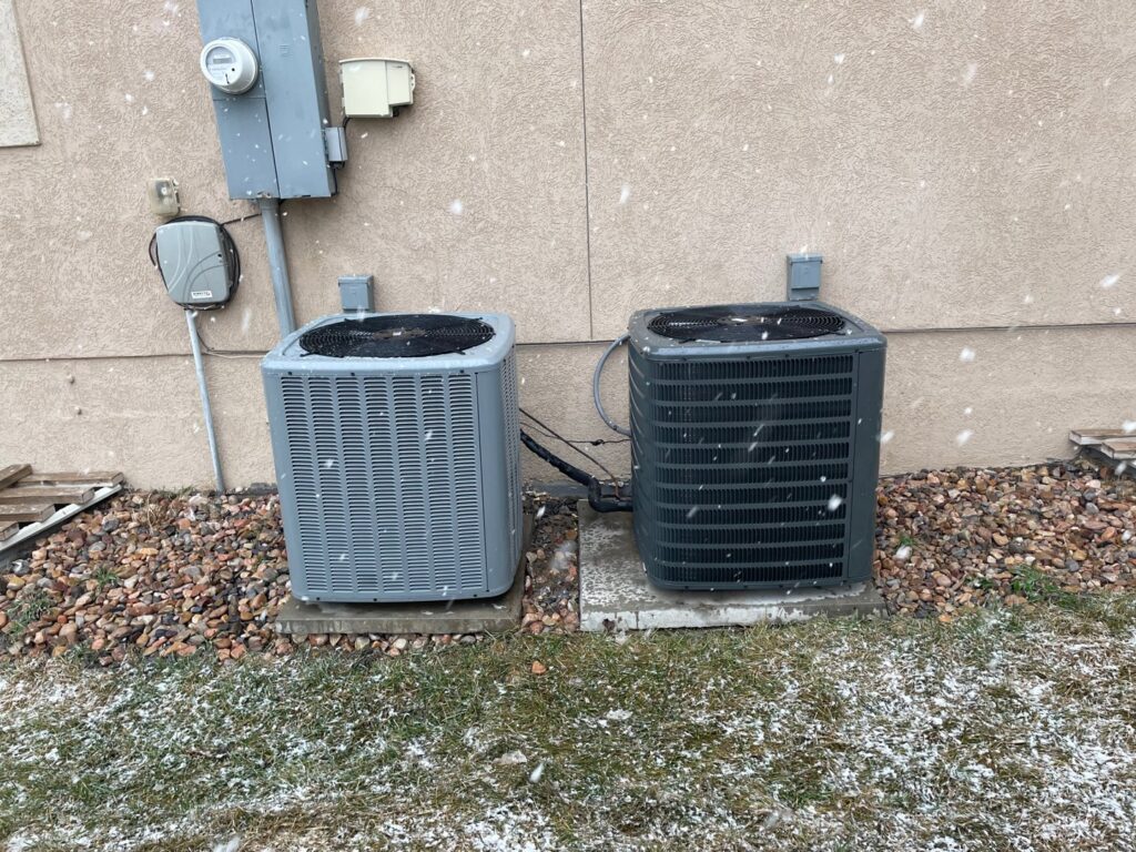 Two outdoor AC condenser units installed next to a home by Simple Valley Heating and Cooling in Orem, UT