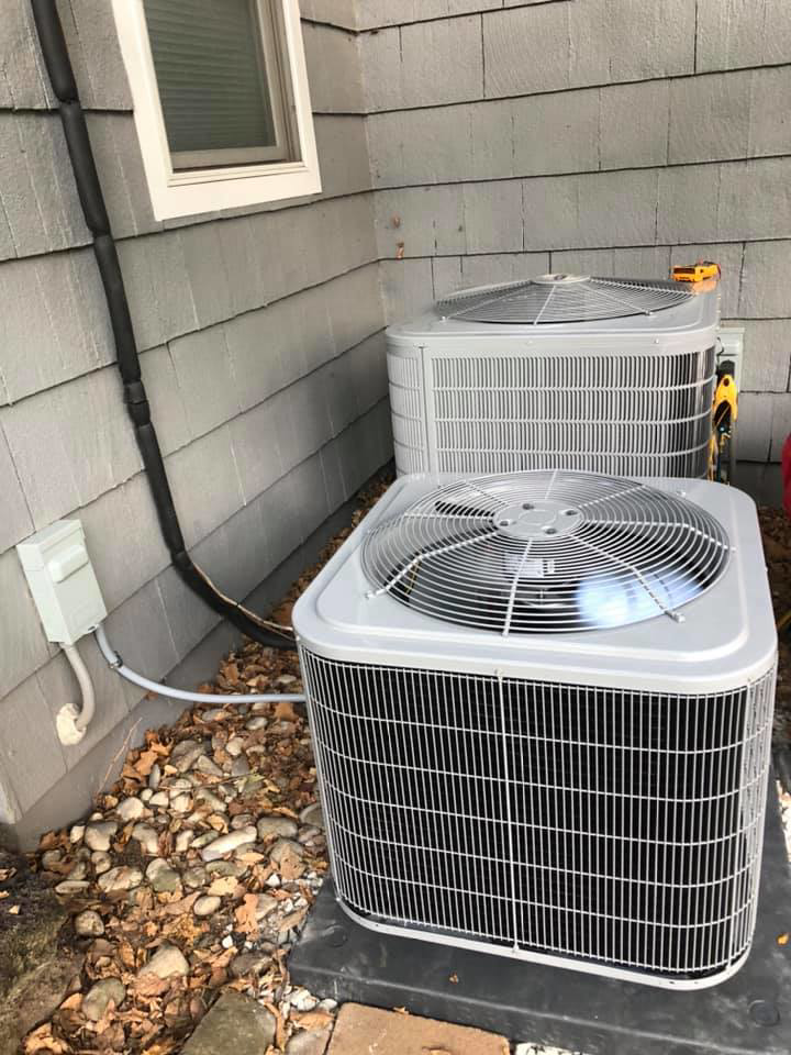 Two outdoor air conditioning units installed next to a residential building by Arrowhead Mechanical HVAC in Woodville, OH