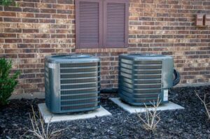 Two outdoor air conditioning units installed next to a brick building by Furnace Doctors Heating & Air Conditioning LLC in Champaign, IL