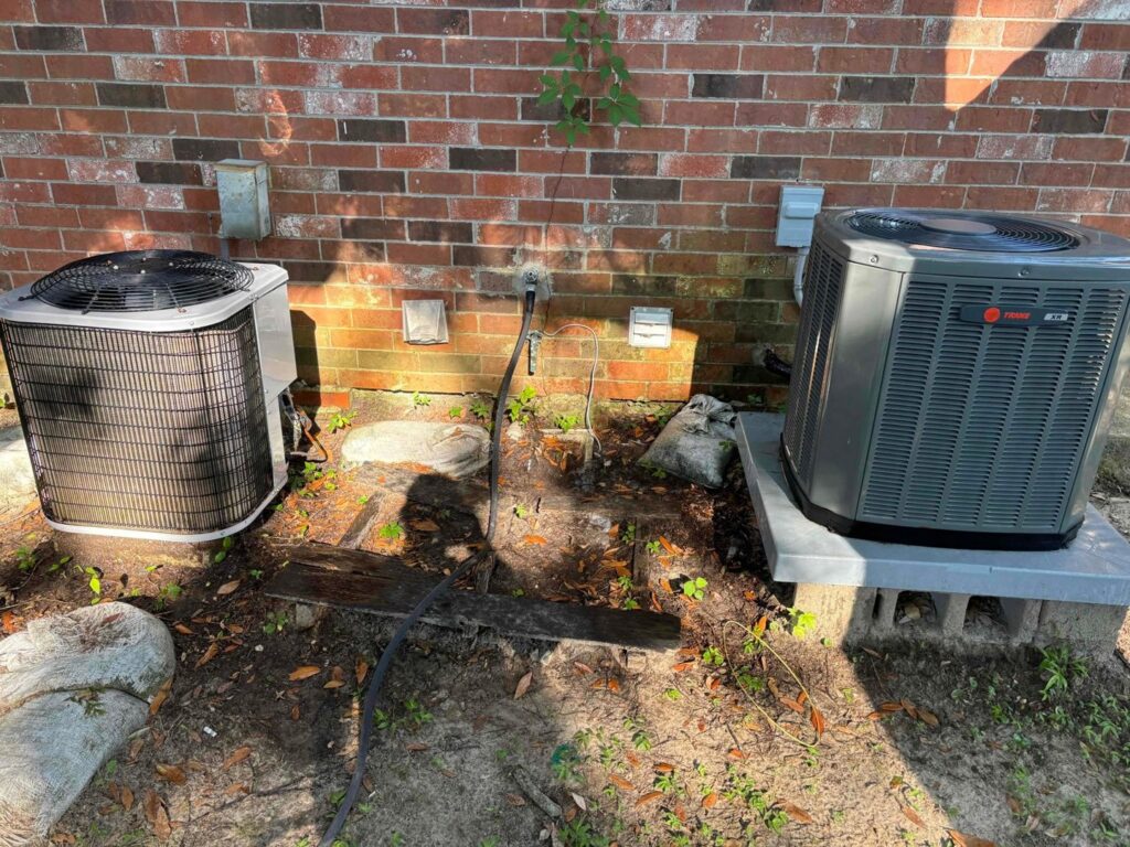 Two outdoor air conditioning units installed next to a brick wall by 5 Star Charleston Heating and Air in Charleston, SC.