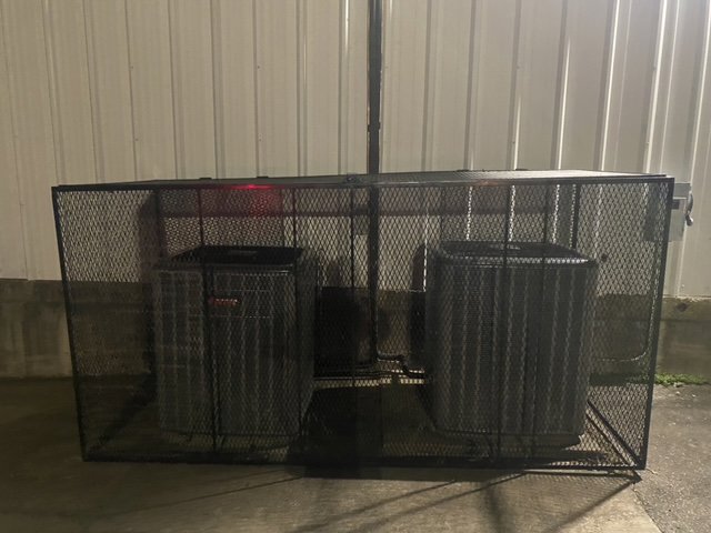Two outdoor air conditioning units enclosed within a large protective metal cage, maintained by Chill Out Heating and Cooling in Tulsa, OK.