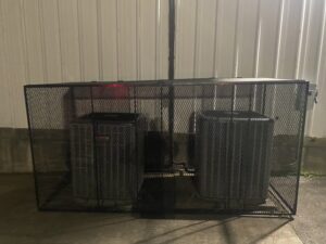 Two outdoor air conditioning units enclosed in a large protective cage by Chill Out Heating and Cooling in Tulsa, OK.