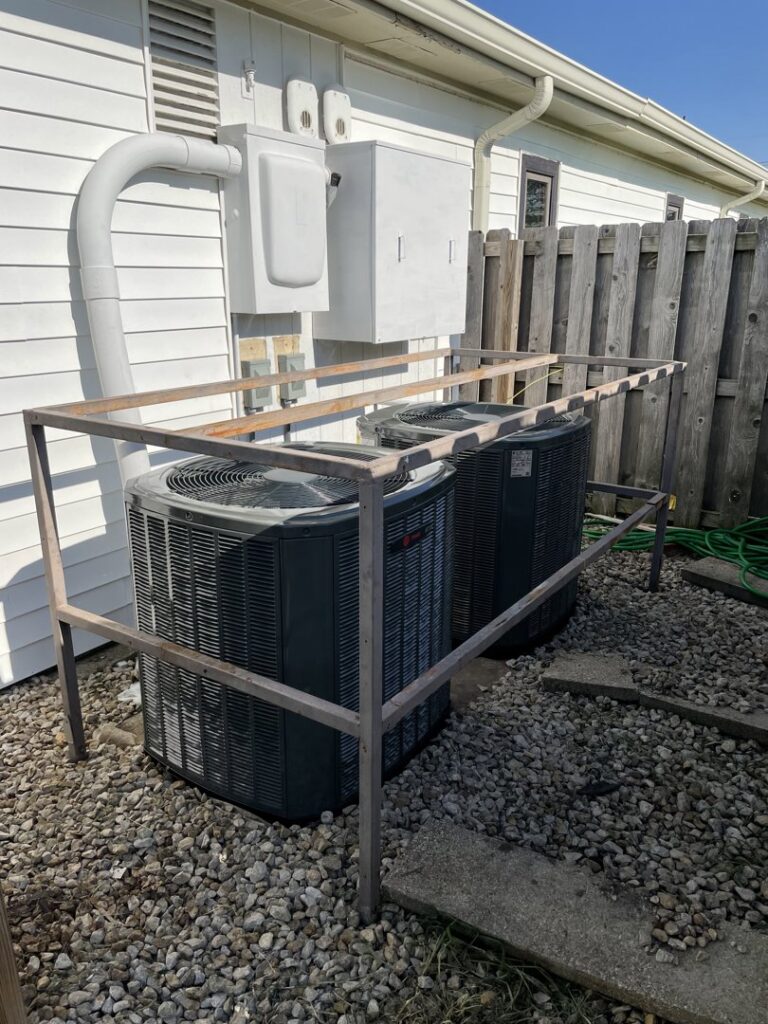 Two outdoor AC units with a protective metal cage installed by A-Team PHC in Olathe, KS.