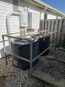 Two outdoor AC units with a protective metal frame installed by A-Team PHC at a property in Olathe, KS.