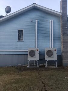 Two outdoor Mitsubishi heat pump units installed on the side of a residential building by Superior CO-OP HVAC in Cambridge, NY.