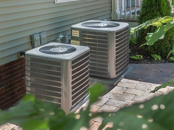 Two outdoor HVAC condenser units installed next to a residential building by Cool Concepts A/C & Heating in San Antonio, TX.
