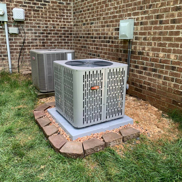 Two outdoor HVAC condenser units installed next to a brick building by Dan Deckard Hvac in Charlotte, NC