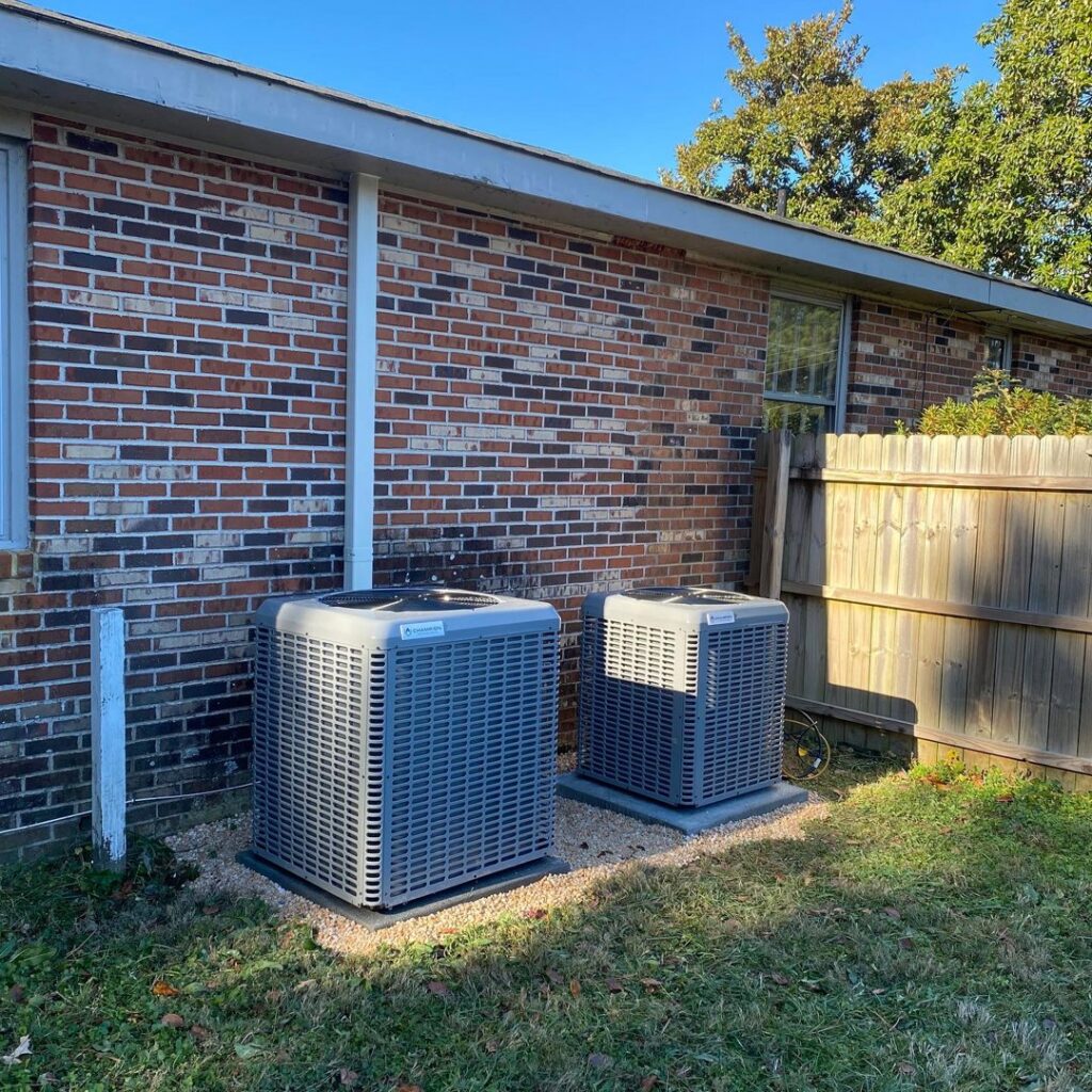 Two outdoor HVAC condenser units installed side-by-side next to a brick home by Coastal Breeze Heating-Cooling-Plumbing in Hampton, VA.