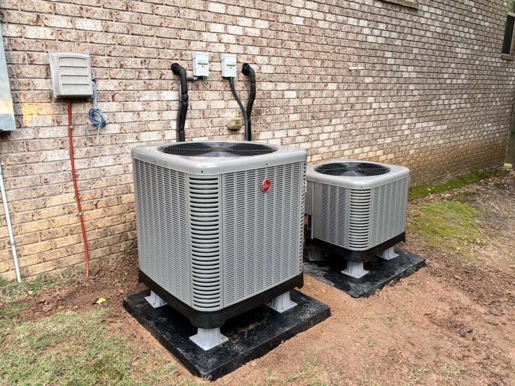 Two outdoor HVAC condenser units installed next to a brick house by ACE Heating & Cooling, Inc. in Jonesboro, AR