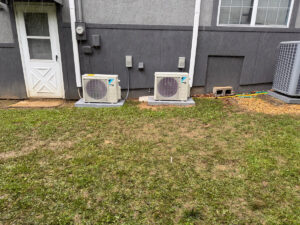 Two outdoor mini-split condenser units installed next to a residential building by Bama Air Systems in Cullman, AL.