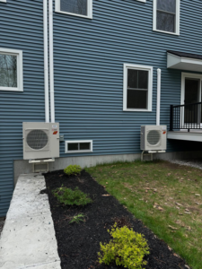 Two outdoor mini-split condenser units installed on a blue house by Infinity Heating and Cooling in Las Vegas, NV.