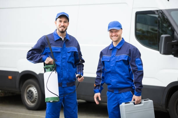 Two pest control technicians with a sprayer and toolbox standing by their van for Grenier's Pest Control in Essex Junction, VT.