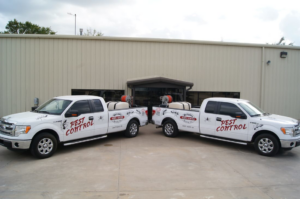 Two white pest control trucks from Reliable Termite of OKC parked outside a commercial building in Oklahoma City, OK.