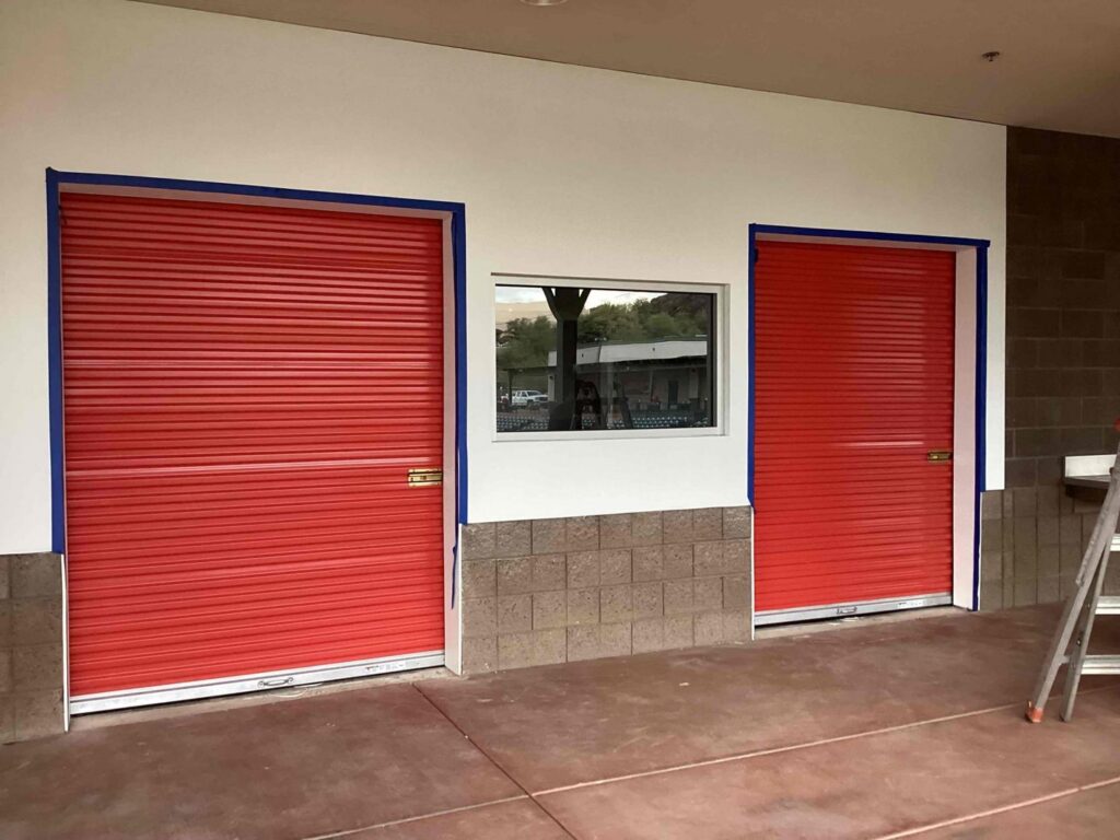 Two red roll-up commercial garage doors installed by Stapley Action Garage Door in Mesa, AZ.