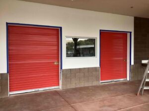 Two red roll-up commercial garage doors installed by Stapley Action Garage Door in Mesa, AZ.