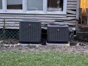 Two Rheem outdoor air conditioning units installed next to a residential building by Total Living Comfort in Irvington, AL.
