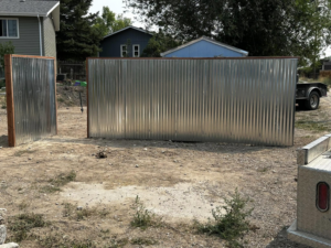 Two sections of corrugated metal fence installed in a residential area by Tomahawk Fencing in Riverton, WY.