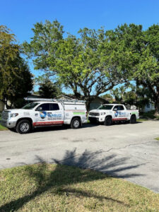 Two Sunbuzz Pest Control & Environmental Services trucks parked on a residential street in Fort Lauderdale, FL.