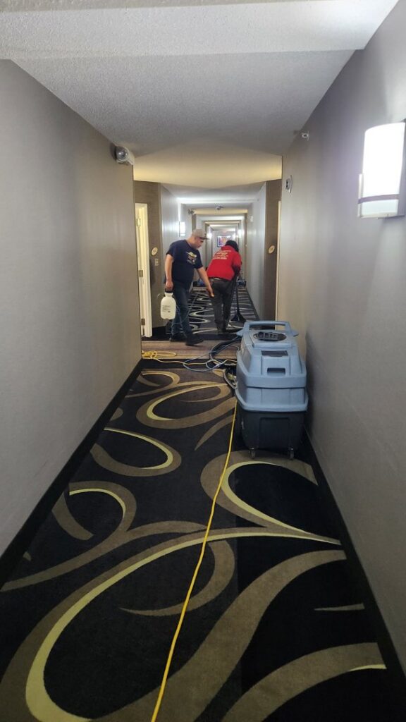 Two InnaCircle technicians performing professional carpet cleaning in a commercial hallway in Greensboro, NC.