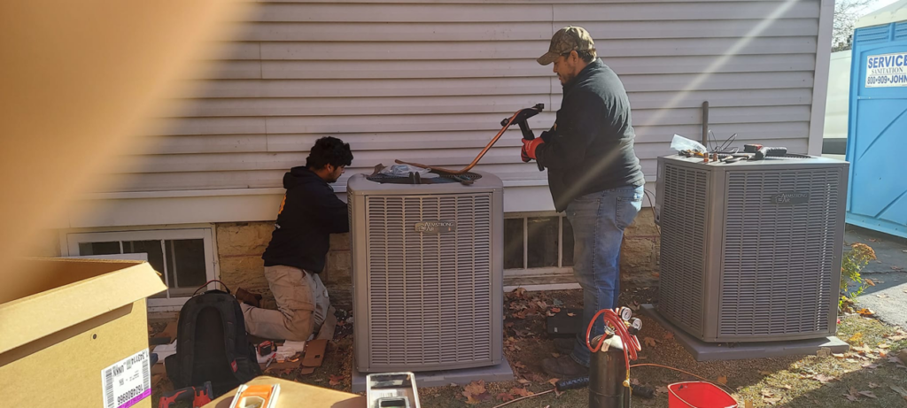 Two technicians installing or servicing outdoor air conditioning units for WC Heating & Cooling Corp. in West Chicago, IL.