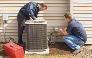 Two technicians servicing an outdoor AC unit for Moore Services Inc. in Brentwood, NY.