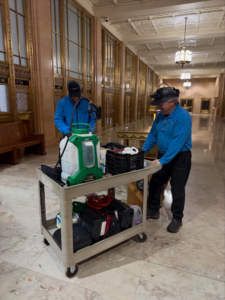 Two Pest Lock, Inc. technicians with pest control equipment on a cart in a large building in Vancouver, WA.