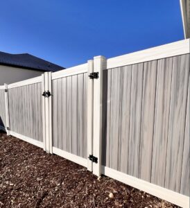 A stylish two-tone composite privacy fence with matching gates installed by Stonehenge Fence & Deck in Orem, UT.