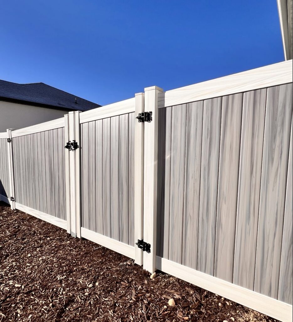 A stylish two-tone composite privacy fence with matching gates installed by Stonehenge Fence & Deck in Orem, UT.