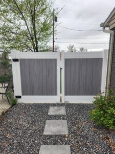 A modern two-tone grey and white vinyl fence with a double gate, installed by All American Vinyl in Provo, UT.